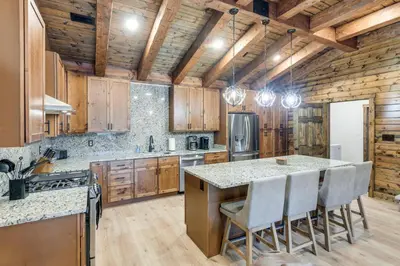 a kitchen with wooden cabinets and a island with bar chairs at Patio and Views Country Getaway in Bluegrass Region in Carlisle