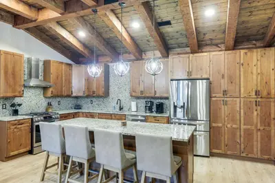 a kitchen with wooden cabinets and a kitchen island with chairs at Patio and Views Country Getaway in Bluegrass Region in Carlisle