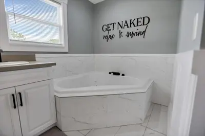 a white bathroom with a tub and a sink at Colonial on Crane in Buckeye Lake