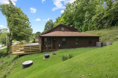 a small house on a hill with a green yard at Lakefront in Logan (In the heart of Hocking Hills) in Logan