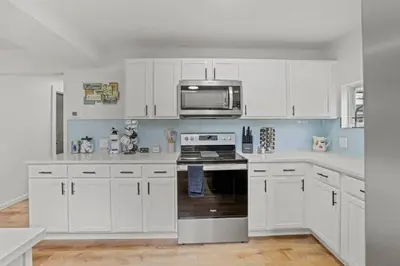 a white kitchen with white cabinets and a microwave at Luxury on Lakeside