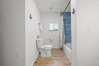 a white bathroom with a toilet and a tub at Luxury on Lakeside