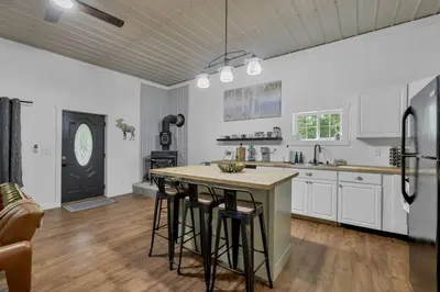a kitchen with white cabinets and a island with bar stools at The Silver Birch in Lancaster
