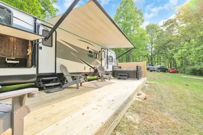 an rv with a wooden deck in a field at Chestnut Camper in Lancaster