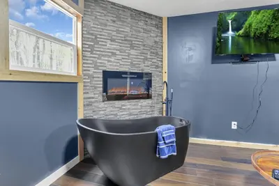 a bathroom with a black bath tub and a tv at The Blue Spruce in Lancaster