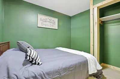 a bedroom with green walls and a bed with pillows at The Evergreen Cabin in Lancaster