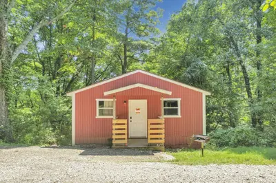 a red shed with a white door in the woods at The Maple Cabin in Lancaster