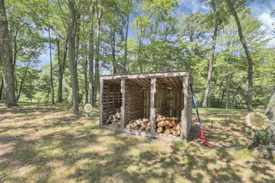 a wooden outhouse with a pile of fire wood at The Maple Cabin in Lancaster