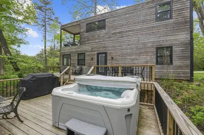 a hot tub on a deck in front of a house at Hiltop Haven The Double Stack in Logan
