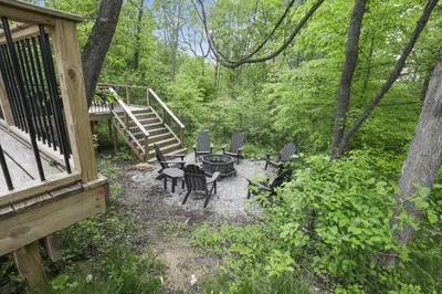 a patio with chairs and a table in the woods at Hiltop Haven The Double Stack in Logan