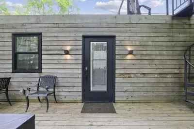 a wooden house with a black door and a chair at Hiltop Haven The Top Deck in Logan