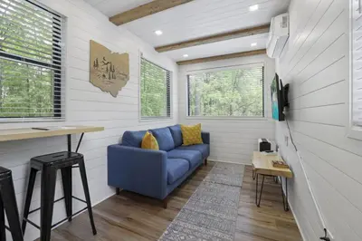 a living room with a blue couch in a tiny house at Hiltop Haven The Top Deck in Logan