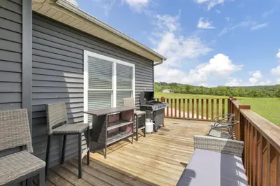 a deck with a grill and chairs on a house at Serenity on Siverly by Purple Munky Hospitality in McArthur