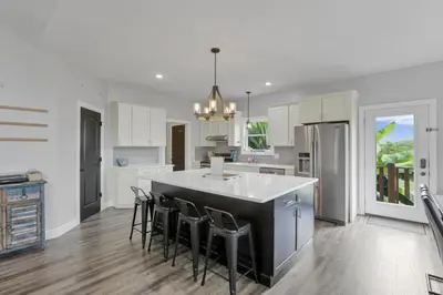 a kitchen with white cabinets and a island with bar stools at Serenity on Siverly by Purple Munky Hospitality in McArthur