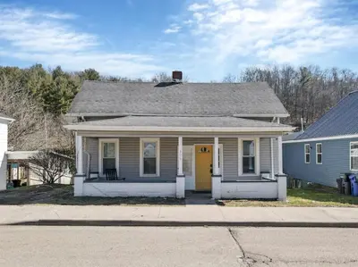a white house with a yellow door on a street at Nostalgic in Nelsonville in Nelsonville
