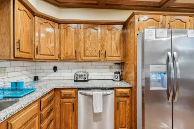 a kitchen with wooden cabinets and a stainless steel refrigerator at Daisy Glen Retreat - Amazing Indoor Pool in South Bloomingville
