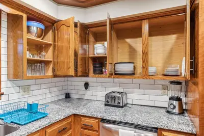 a kitchen with wooden cabinets and plates on the counter at Daisy Glen Retreat - Amazing Indoor Pool in South Bloomingville