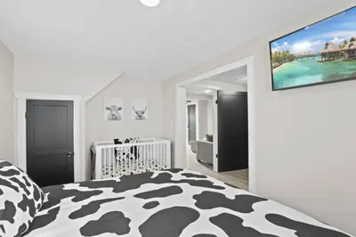 a white bedroom with a black and white bed and a crib at Cattle Cottage