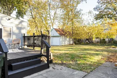 a house with a porch with a staircase and a yard at Euclid Near Lake Erie Cleveland king bed in Euclid