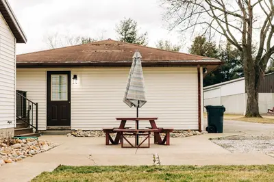 a picnic table with an umbrella in front of a house at Grandma's Place - Steps from Downtown Sugarcreek in Sugarcreek