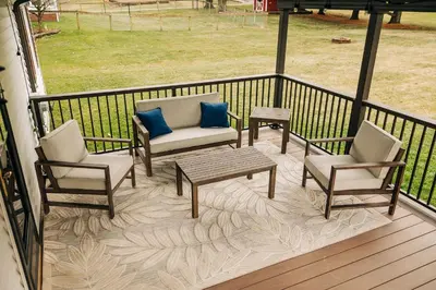 a porch with two chairs and a table and two blue pillows at Grandma's Place - Steps from Downtown Sugarcreek in Sugarcreek