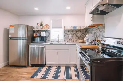 a kitchen with white cabinets and a stainless steel refrigerator at Grandma's Place - Steps from Downtown Sugarcreek in Sugarcreek