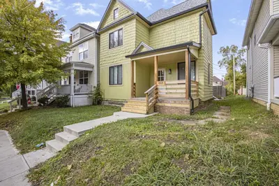 a yellow house with a porch and a yard at Victorian Villa in Columbus