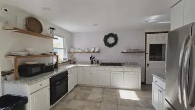 a kitchen with white cabinets and a refrigerator at Lincoln House Inn in Bowling Green