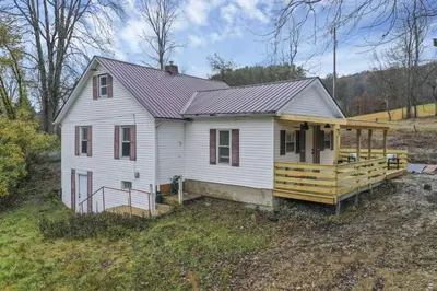 a white house with a porch and a deck at Mirror Pond Cabins in Rockbridge