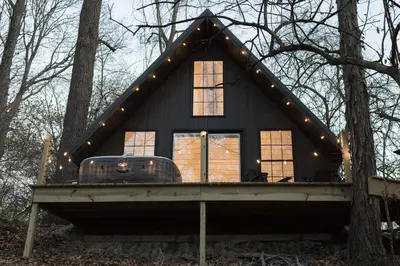 a tiny house in the woods with lights on it at Liv's Treehouse-Honeymoon Suite-Hot Tub in Milroy
