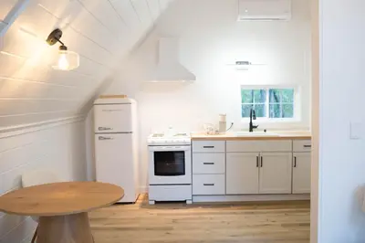 a kitchen with white appliances and a wooden table at Liv's Treehouse-Honeymoon Suite-Hot Tub in Milroy
