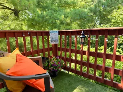 a deck with a chair and a sign on a fence at Avon Nature Retreat by Creek in Avon