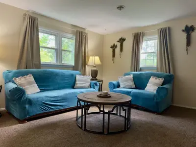a living room with two blue couches and a table at Avon Nature Retreat by Creek in Avon