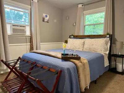 a bedroom with a bed with a blue blanket and two windows at Avon Nature Retreat by Creek in Avon