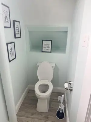 a bathroom with a toilet with two pictures on the wall at 3 bed room 5 beds 1 bath sleeps 6 guest in Hamilton