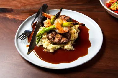 a plate of food with shrimp and rice and sauce at Kimpton Schofield Hotel by IHG in Cleveland