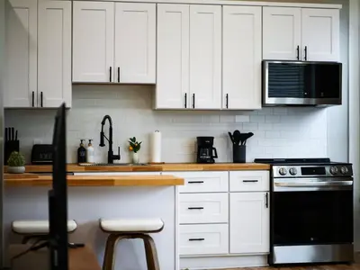 a kitchen with white cabinets and a black appliance at The Modern Boho Brick Loft in Cleveland