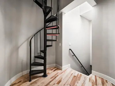 a black spiral staircase in a room with wooden floors at The Modern Boho Brick Loft in Cleveland