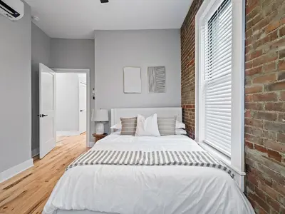 a bedroom with a white bed and a brick wall at The Modern Boho Brick Loft in Cleveland