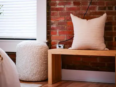 a pillow sitting on a bench next to a brick wall at The Modern Boho Brick Loft in Cleveland