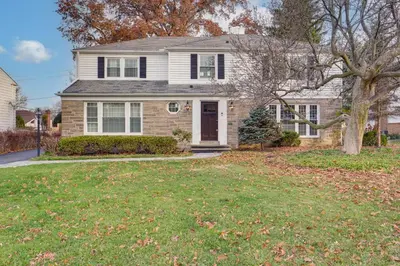 a white house with a tree in the yard at Explore Cleveland Attractions! Family-Focused Home in Shaker Heights