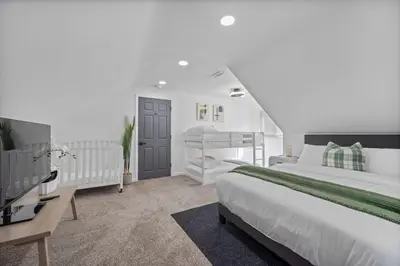 a white bedroom with a bed and a tv at Luxury 5BR Cincinnati, Sleeps 12, Crib, Home Gym, Fenced Backyard in Cincinnati