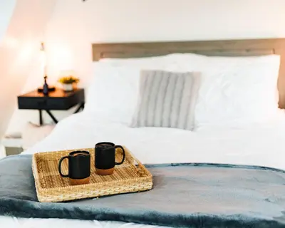 two coffee mugs on a tray on a bed at The Pinnacle in Logan
