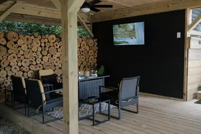 a patio with chairs and a table and a pile of logs at The Pinnacle in Logan