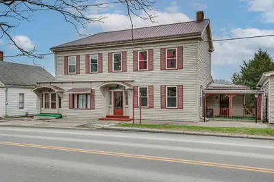 a white house with a red door on a street at 5 Mi to The Wilds Spacious Family Hub, Game Room!