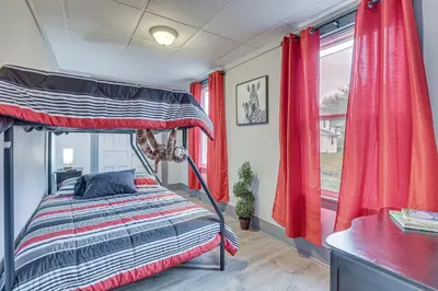 a bedroom with a bed with red curtains and a window at 5 Mi to The Wilds Spacious Family Hub, Game Room!