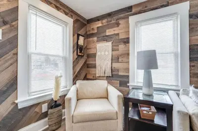 a living room with wooden walls and a chair and a table at Cozy Old Brooklyn Home near Zoo in Cleveland