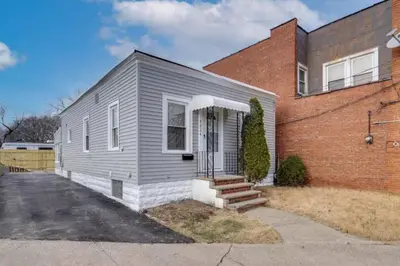 a gray house is next to a brick building at Cozy Old Brooklyn Home near Zoo in Cleveland