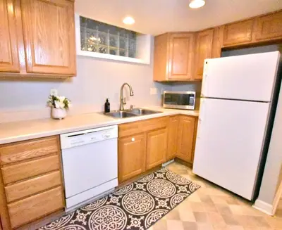 a kitchen with wooden cabinets and a white refrigerator at Tremont apartment, near downtown, and Central! in Cleveland