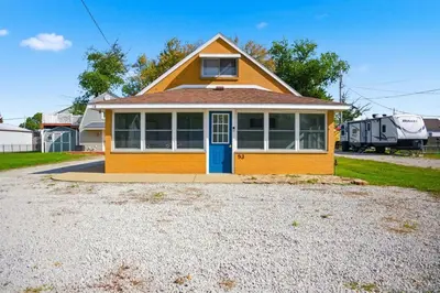 a small yellow house with a blue door at Angler's Cottage with Boat Parking by Lake Erie in Port Clinton